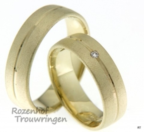 Brede trouwringen met een unieke uitstraling in het geelgoud. De prachtige trouwringen set heeft een subtiele diamant in het midden van de ring.