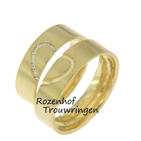 Romantische trouwringen! Deze trouwringen zijn vervaardigd in het geelgoud en hebben een breedte van 6 mm. Wat deze ringen zo romantisch maakt is het hartvorm wat ze samen vormen! In de dames trouwring zitten er zeven briljant geslepen diamanten in verwerkt.