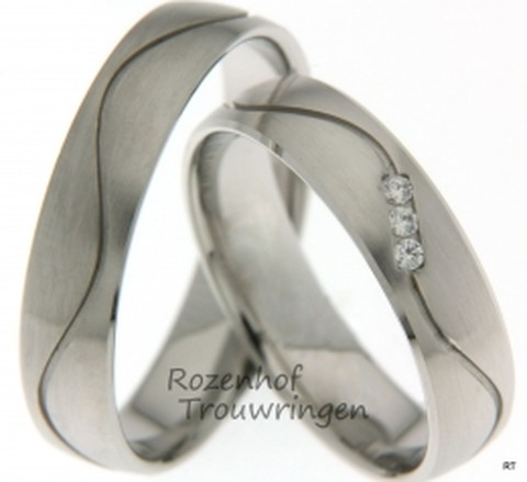 Witgouden trouwringen van 5 mm breed met 3 briljant geslepen diamanten van samen 0,045 ct. Een golvende lijn doorbreekt het strakke ontwerp van de ringen.