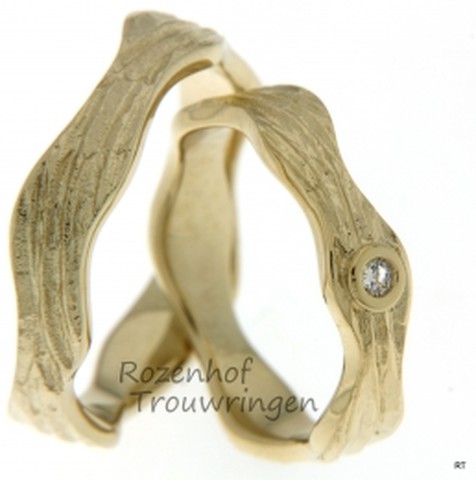 Ambachtelijke kunst in geelgoud!Een waar kunstwerk, deze 5,8 mm brede grillig gevormde trouwringen van geelgoud. Als een kronkelende slang vormt deze ring zich om uw vinger. In de dames trouwring is een briljant geslepen diamant gezet van 0,055 ct.