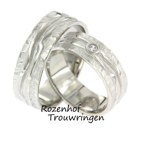 Deze prachtige trouwringen zijn uitgevoerd in witgoud met een breedte van 6,7 mm. De ringen zijn gemaakt in een ambachtelijke stijl. In de damesring is een briljant geslepen diamant gezet van 0,045 ct. Deze ringen zijn ook leverbaar in palladium of platina.