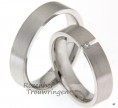 Moderne witgouden trouwringen met matte finish, die opvallen door hun strakke vormgeving. De ringen zijn 5 mm breed. De dames trouwring is bezet met een briljant geslepen diamant van 0,03 ct, die opvalt door zijn unieke plaatsing.