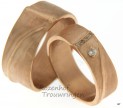 Warme roodgouden, ambachtelijke trouwringen. Verkrijgbaar in 7 mm breed of 9 mm breed. De oneffen, satijnmatte ring wordt onderbroken door glanzende paden. In de dames trouwring zijn 4 kleinere en 1 grote briljant geslepen diamanten geplaatst, welke schitteren in de ring.