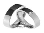 Tegenstrijdige trouwringen van witgoud en ruthenium. De tegenstrijdigheid in kleur is wat extra opvalt in dit moderne model. In de dames trouwring prijkt een beeldschone, baquette geslepen diamant van 0,06 ct. De ringen zijn 5 mm breed.
